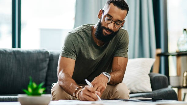 Shot of a young man going over his finances at home