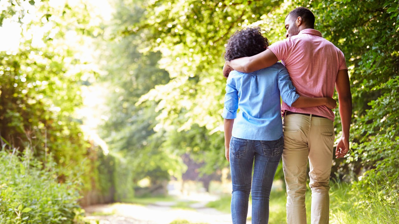 couple walking arm in arm in the woods