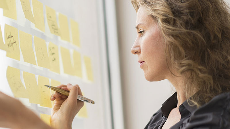 woman writing on post it notes on the wall