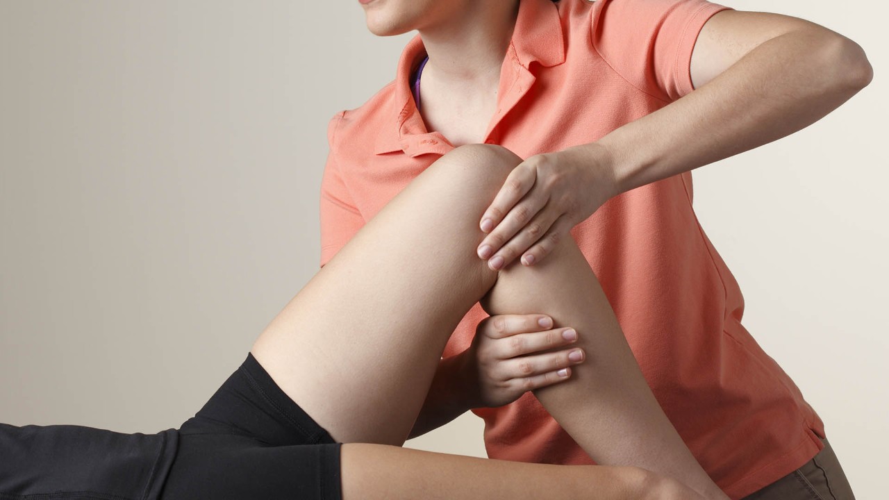 physical therapist stretching a patient's knee