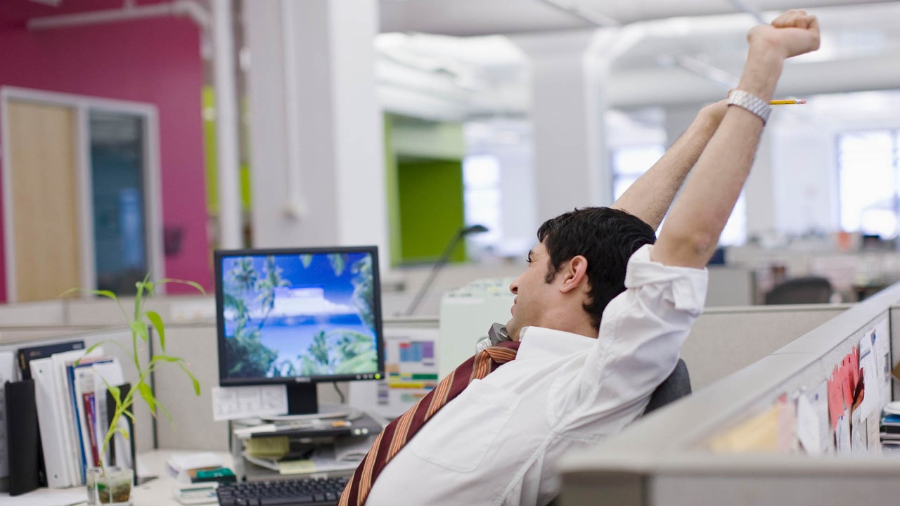 man stretching at his desk at work