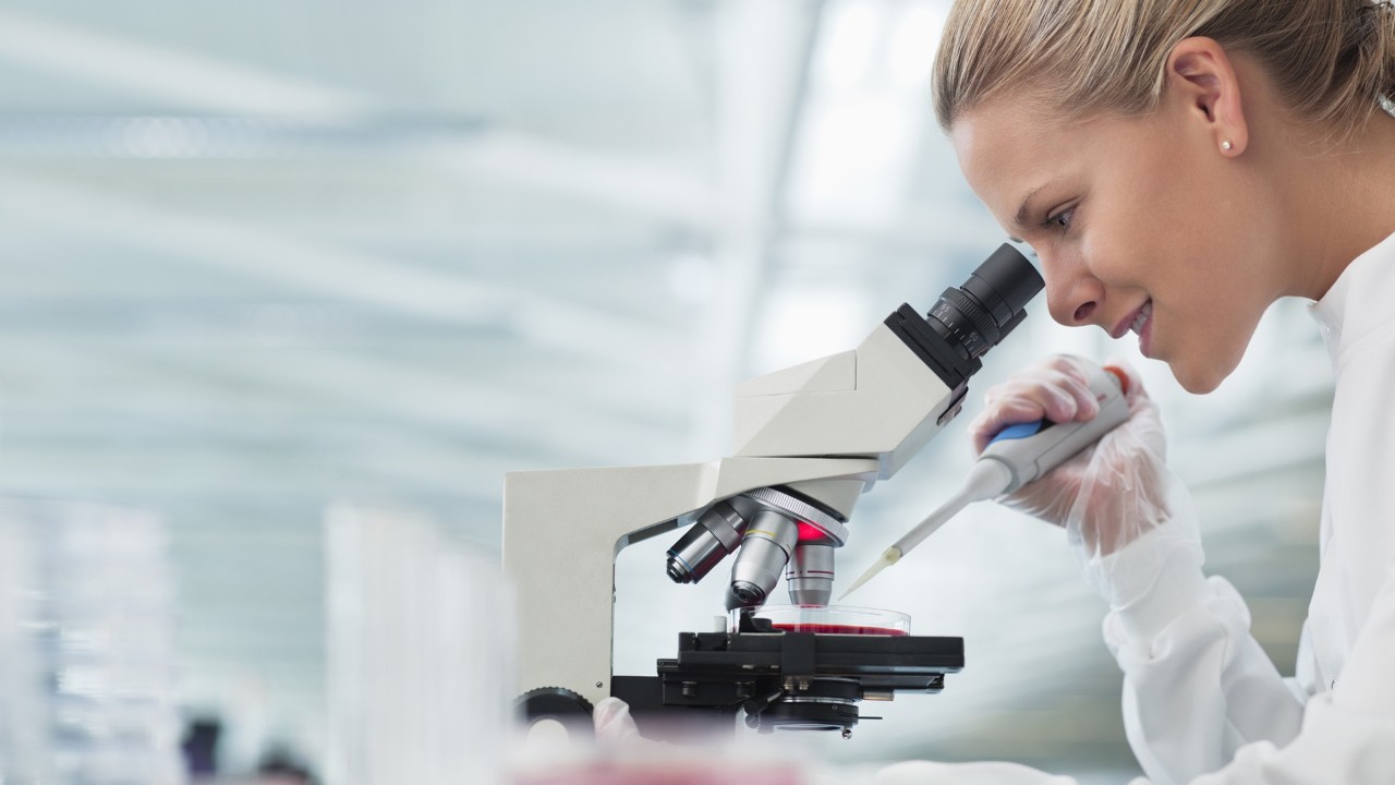 scientist looking though a microscope