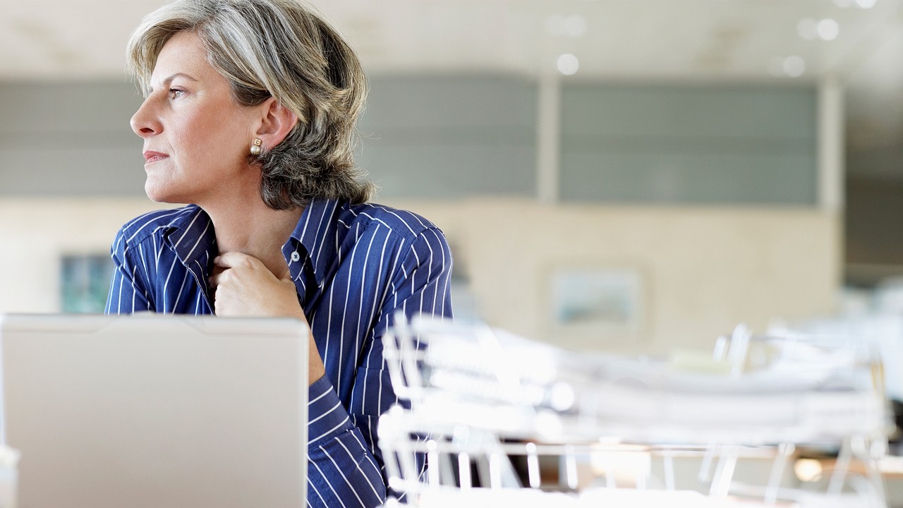 woman looking out the window at her desk