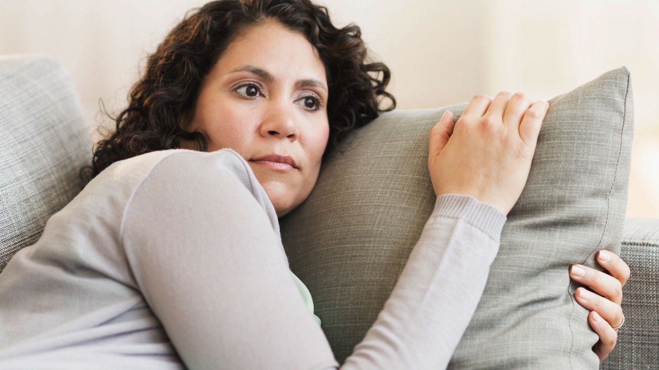 woman holding a pillow on the couch looking onward