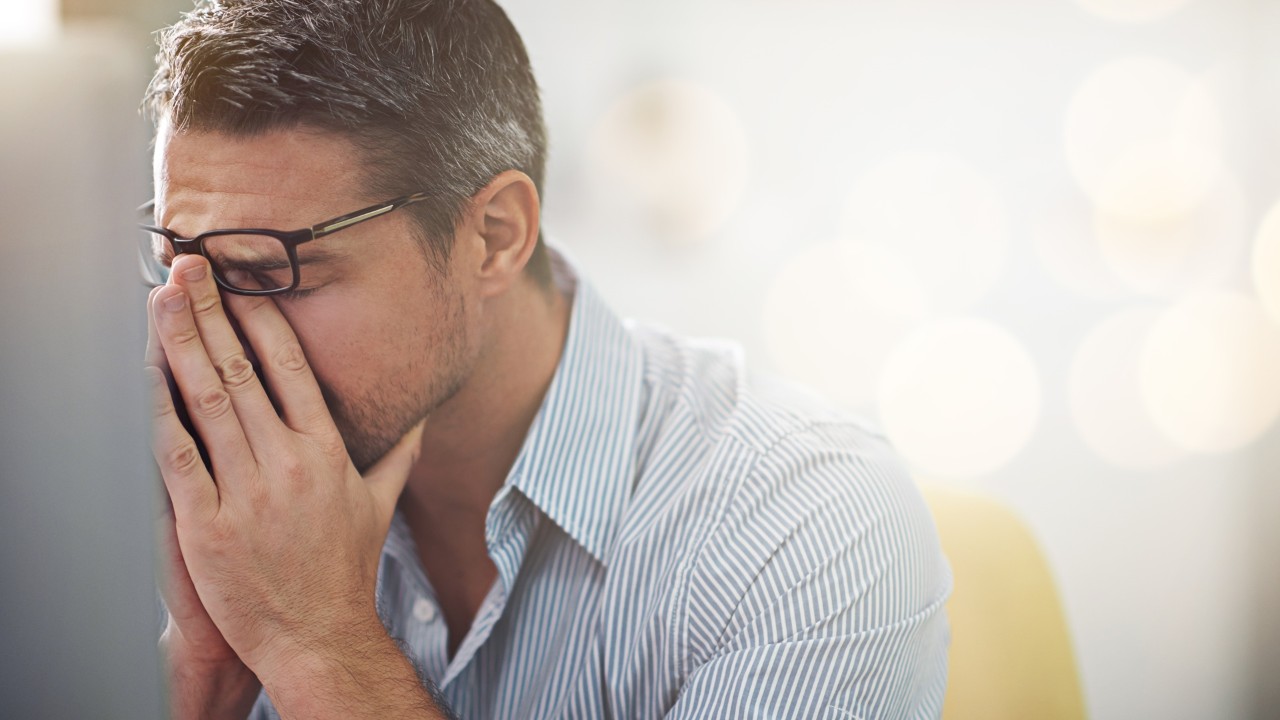 man rubbing his eyes under is glasses