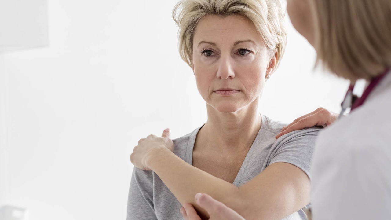 woman holding her shoulder at doctor's office