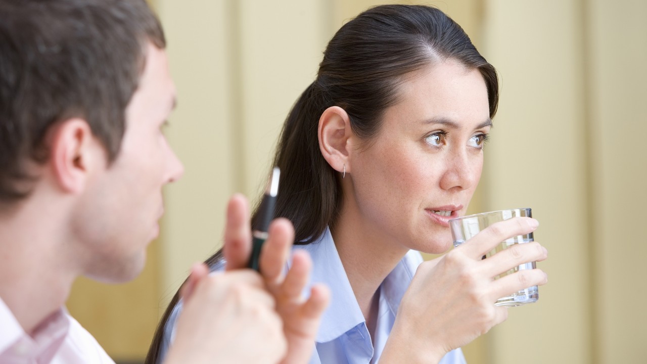 woman drinking a glass of water next to a man